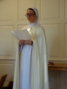 Nun in white habit standing and reading from document