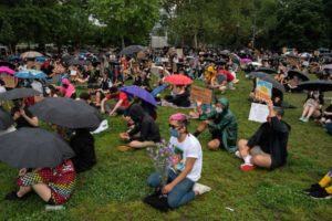 protesters wearing masks and sitting in green lawn