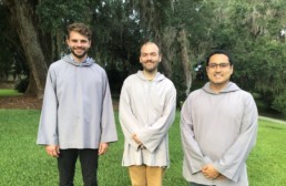 Three smiling men in grey smocks