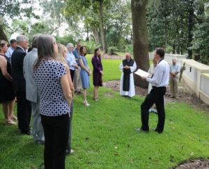 group stands on grass listening to service at Mepkin Columbarium wall
