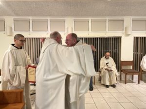 Fr. Paul Mark receives congratulary hug from fellow monk in cowl
