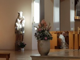 Statue of Jesus and Mary, beside a monk kneeling in prayer