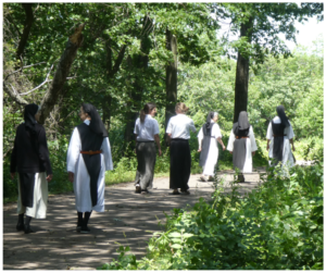 nuns walking on wooded path