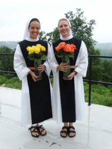 Sister Mary and Sister Annie smile holding vases with flowers