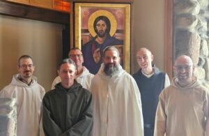 A group of monks at Genesee Abbey pose in front of an icon of Christ Pantocrator