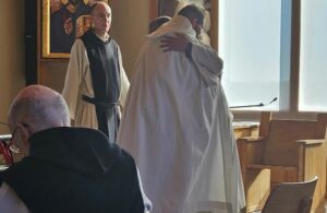 Brother Mark receiving embrace from the abbot as he is clothed as a novice at Genesee Abbey