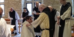 Br. Phillip kneels before the Superior of New Melleray Abbey, receiving the white novice habit