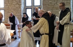 Br. Phillip kneels before the Superior of New Melleray Abbey, receiving the white novice habit