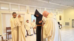 Brother Simon is clothed in the black scapular and leather belt of a proffessed monk of New Clairvaux Abbey by Abbot Paul-Mark Schwan as the monastic community looks on.